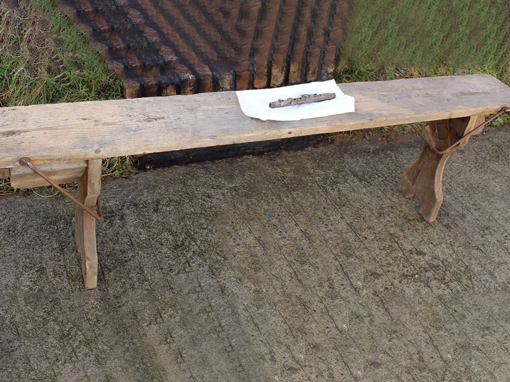 A Folding bench from the Fron-goch Internment Camp in Wales with a flute found in the Camp site
